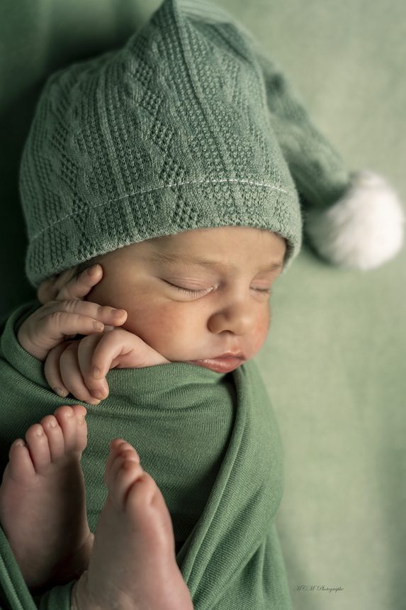 Séance Hana : nouveau-né emmailloté au bonnet, sur fond vert